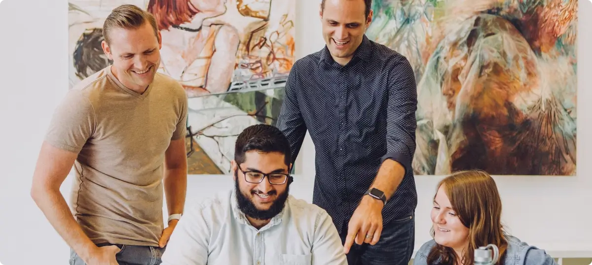The BoardroomUK team collaborating around a laptop